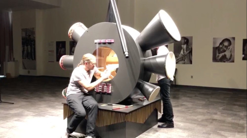 
     
     <i>Resonator</i>,      2018<br />
     wood, metal, harp, chimes, drums, didgeridoos, aabguitar, mame and strings, goatskin, 
      314 x 242 x 228 cm<br />
     Activation at 